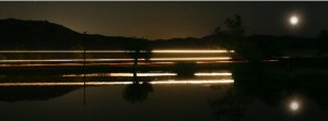 A train passing by the lake at the RV Park in Redlands during a full moon.